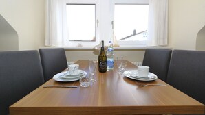 Une table à manger dressée avec des assiettes, des verres, des couverts et une bouteille d’eau.