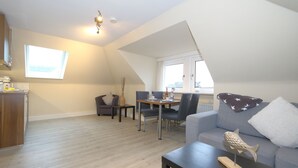 Un salon moderne avec un coin repas, une chambre à l’étage avec un plafond en pente et une vue sur la ville.