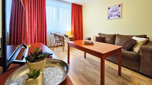 Un salon avec une table en bois, un canapé, un fauteuil et un téléviseur.