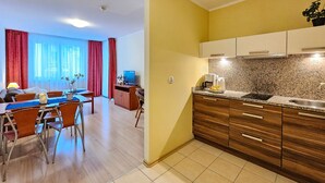 A modern hotel room with a dining area, kitchenette, and a large window with curtains. - Naut 310 - Nautilius (Swinoujscie)