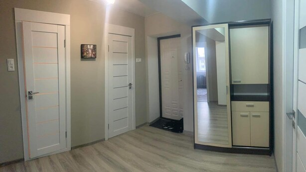 A hallway with three doors, a small framed picture on the wall, and a mirrored closet with a black countertop. - Lovely Brand New Apartment with 2 Rooms and Balcony  (Chișinău)