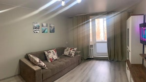 A living room with a sofa, a TV, and a window with curtains. - Lovely Brand New Apartment with 2 Rooms and Balcony  (Chișinău)