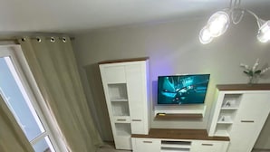A modern living room with a flat-screen TV, white cabinetry, and a brown sofa. - Lovely Brand New Apartment with 2 Rooms and Balcony  (Chișinău)
