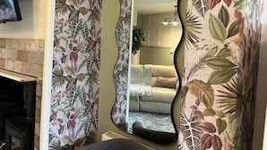 Una habitación con chimenea, un sofá y un espejo grande que refleja el interior.