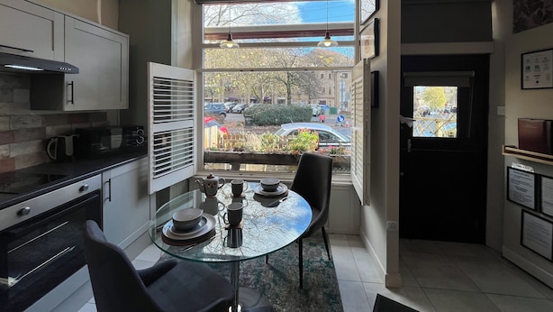 Una cocina moderna con una mesa de comedor de vidrio, sillas negras y vistas a la calle.