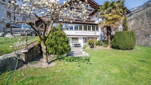 A hotel with a garden, a car, and a mountain in the background. - Holiday Apartment 'Camping Passeier Apfelblüte' with Mountain View, Garden & Wi-Fi (Saltaus)