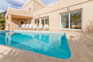 Ein modernes Gebäude mit Schwimmbad, Liegestühlen und einer Terrassenfläche.
