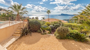 Ein Garten mit einer Palme, einer Treppe und Blick aufs Meer.