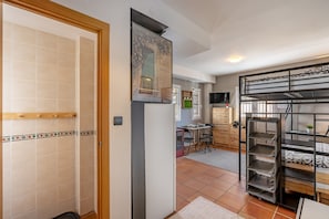 Un espace de vie compact comprenant un coin cuisine, un coin repas et un espace nuit avec des lits superposés.