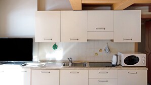 Une cuisine avec des armoires blanches, un four à micro-ondes, un évier et une cuisinière.
