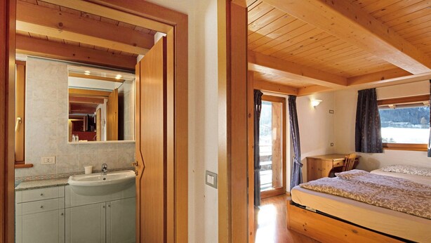 Une chambre à coucher avec un lit en bois, une table de chevet et une fenêtre avec des rideaux.
