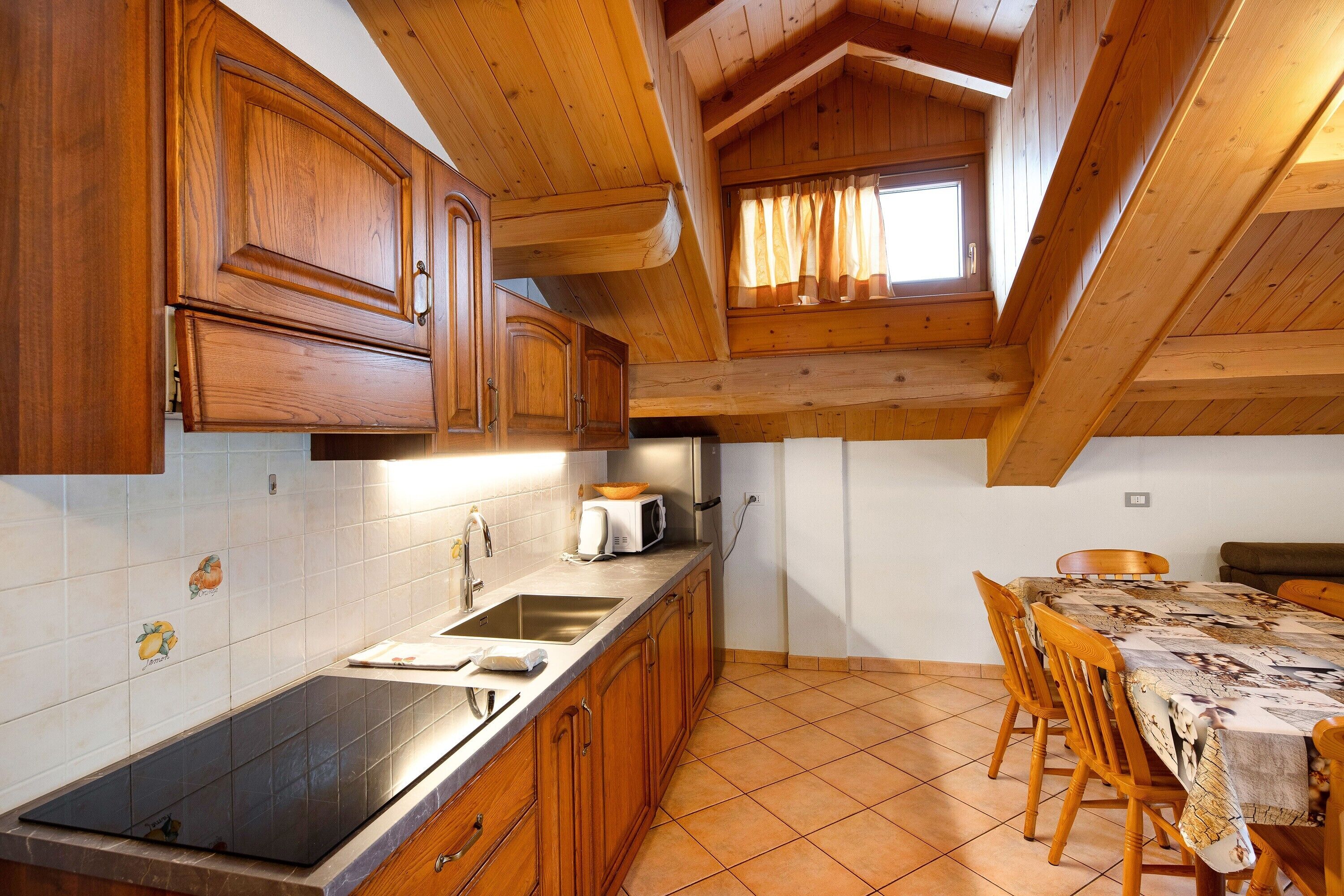 Une cuisine avec des meubles de rangement en bois, un évier, un four à micro-ondes et une table à manger avec des chaises.