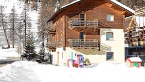 A wooden chalet with a balcony, a small porch, and a snow-covered ground. - Paradisin Apartment with Mountain Views (Livigno)