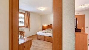 A bedroom with a wooden bed, a desk, and a chair. - Paradisin Apartment with Mountain Views (Livigno)