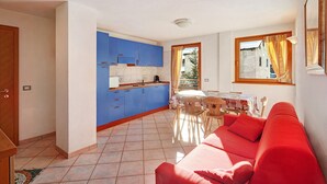 A compact living space with a kitchenette, a dining area, and a red sofa. - Paradisin Apartment with Mountain Views (Livigno)