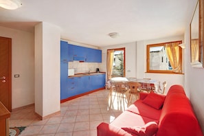 A compact living space with a kitchenette, a dining area, and a red sofa.