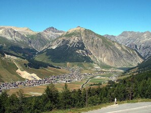 A mountainous landscape with a valley, a small settlement, and a road.