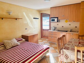 Ein kleines Schlafzimmer mit Bett, einer Küchenzeile und einer Badezimmertür.