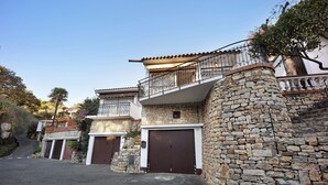 A residential building with stone walls, a balcony, and a garage.