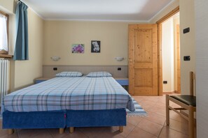 A bedroom with a bed, a chair, a wooden door, and two wall-mounted light fixtures.