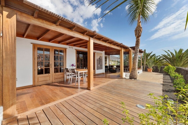 A wooden deck with a covered patio area, a dining table, and chairs.