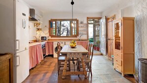 A kitchen with a dining table, chairs, a refrigerator, a washing machine, and wooden cabinets.