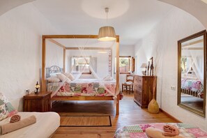 A bedroom with a four-poster bed, wooden furniture, a mirror, and a bedside table with a lamp. - Holiday Home Casa Inma with Pool, Garden and Wi-Fi (Vejer de la Frontera)