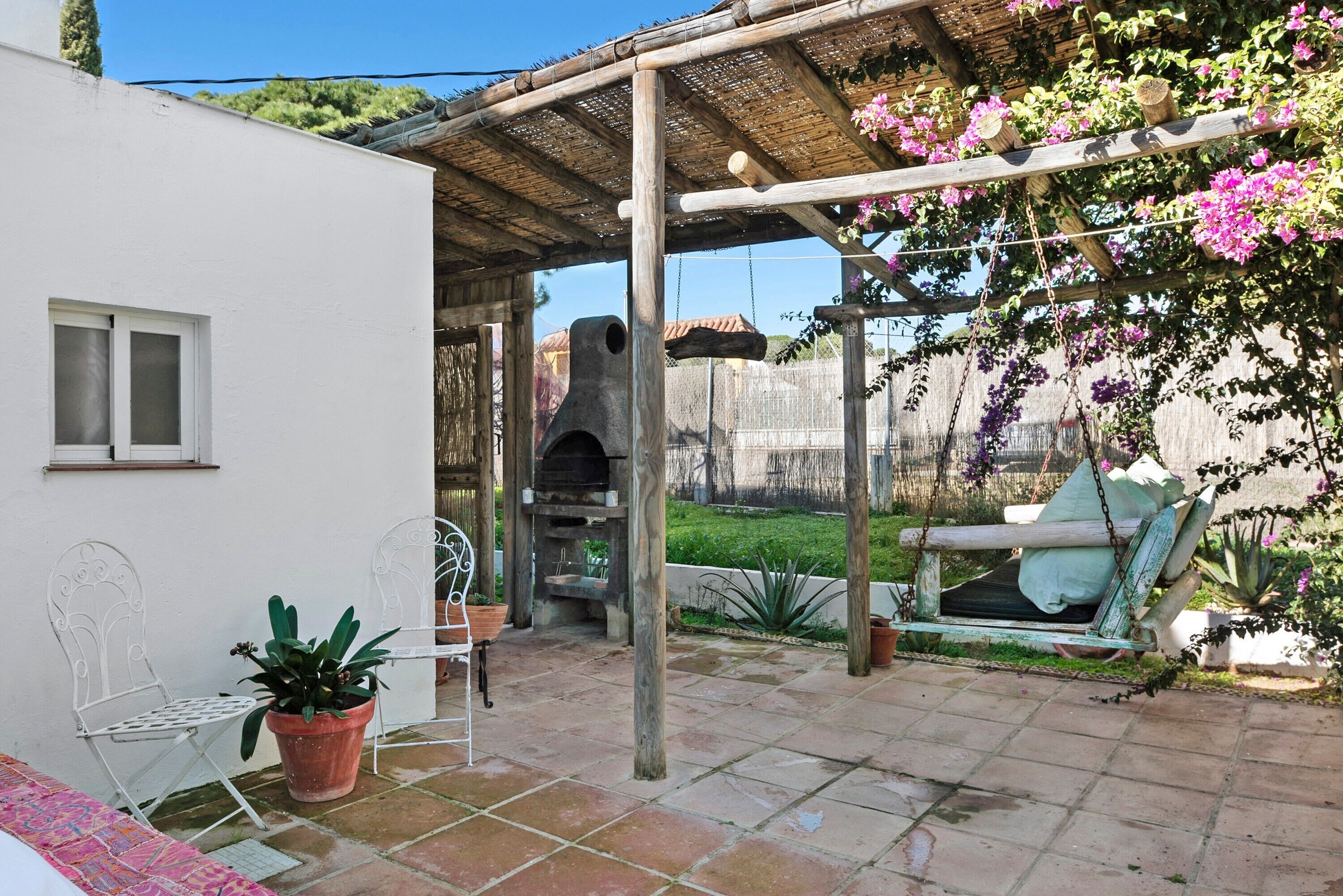 Eine Terrasse mit Grill, Stühlen und einer Schaukel.