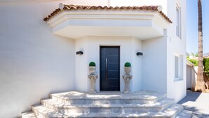 Um edifício com porta preta, paredes brancas e telhado telhado.