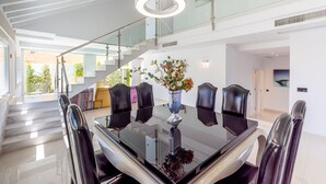 Uma área de jantar moderna com mesa de vidro, cadeiras pretas e um vaso de flores.