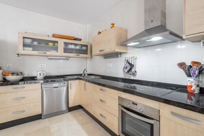 Een moderne keuken met roestvrijstalen apparatuur, houten kastjes en een zwart aanrecht.