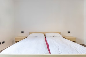 A single bed with a wooden headboard and two bedside tables.
