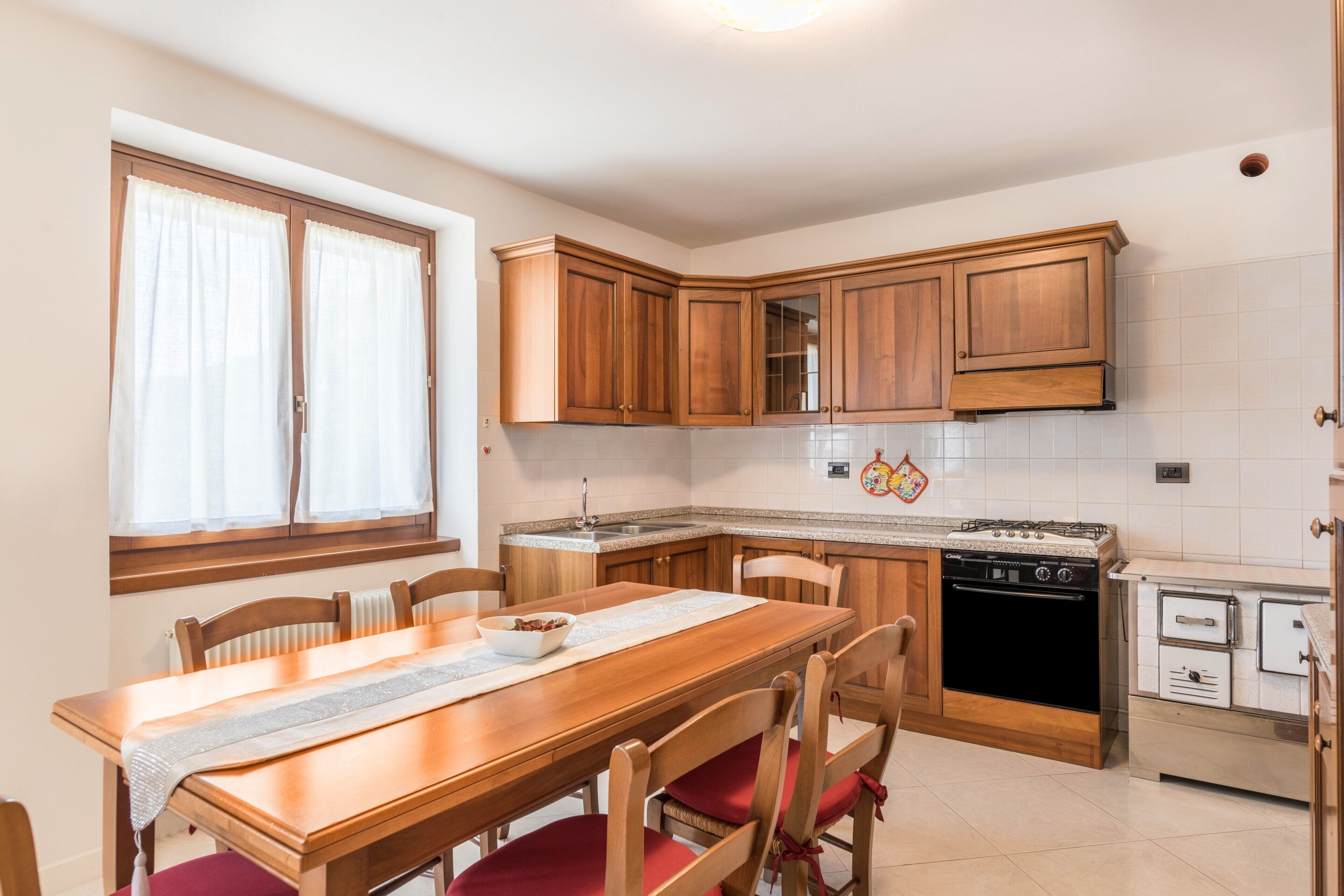 Una cocina con armarios de madera, una mesa de comedor con sillas, una estufa y un lavavajillas.