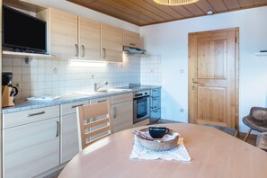 A kitchen with wooden cabinets, a built-in oven, and a dining table with a bowl.