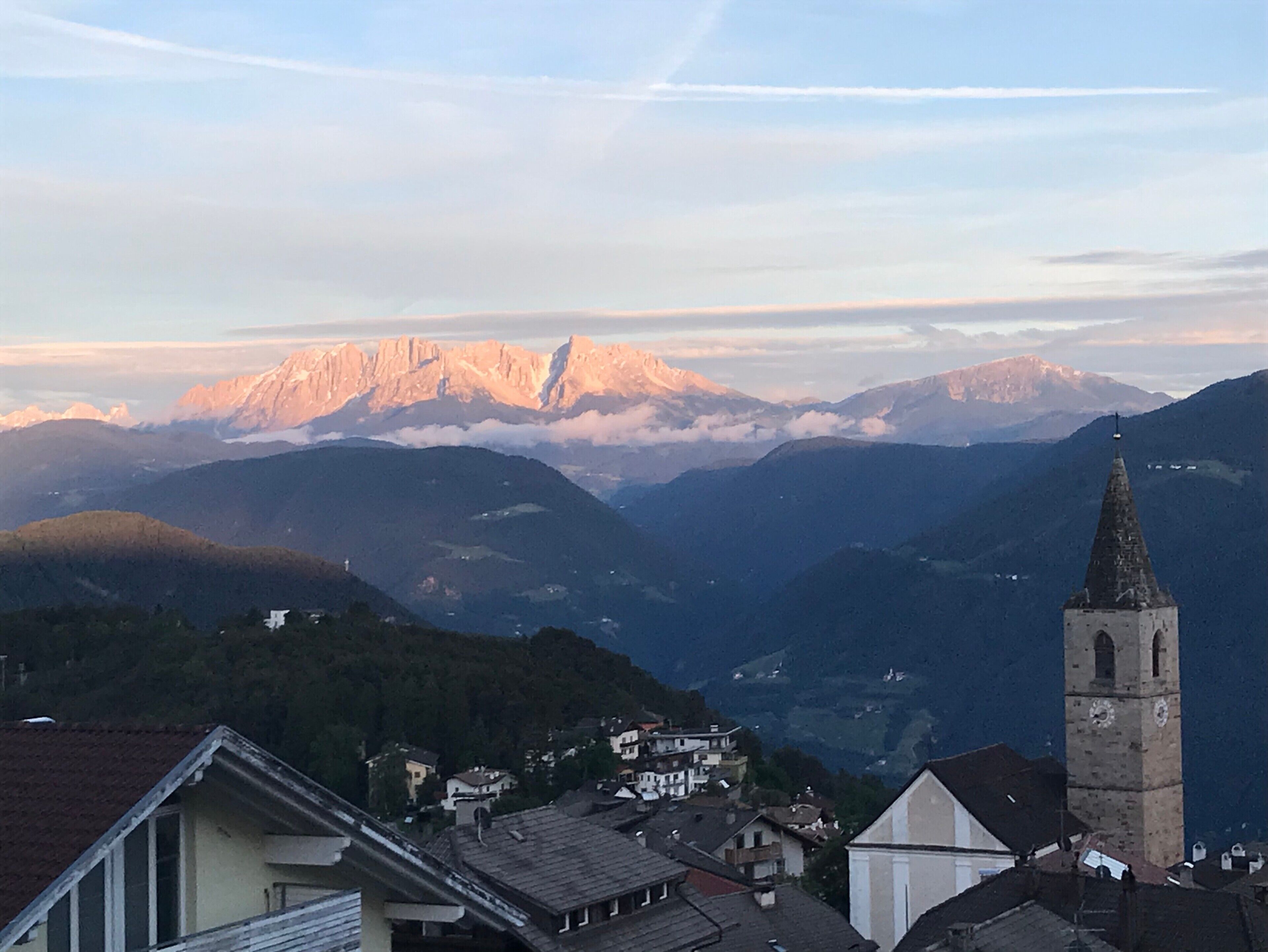 Un paysage de montagne avec un clocher d’église et des immeubles d’habitation.