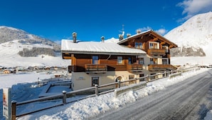 A chalet-style building with a wooden facade, balconies, and a snow-covered roof. - Chalet Betty Appartamento Pec with Mountain View (Livigno)