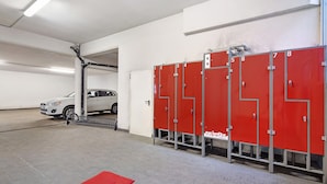 A parking garage with lockers numbered 1 to 8, a white car, and red benches. - Chalet Betty Appartamento Pec with Mountain View (Livigno)