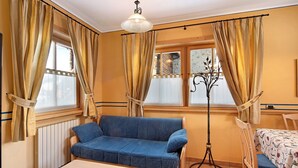 A room with a sofa, a table, a chair, and a floor lamp. - Chalet Betty Apartment Muf with Mountain View, Wi-Fi, Balcony & Garden (Livigno)