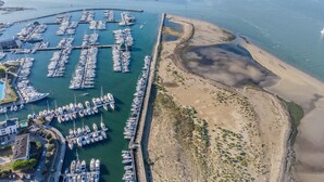 Luchtbeeld van een jachthaven met veel boten in de haven, een zandstrand en een helder uitzicht op het water.