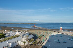 Une plage avec une jetée, des parasols et un phare.