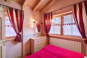 Une chambre à coucher avec un lit, une commode, un miroir et des rideaux à la fenêtre.