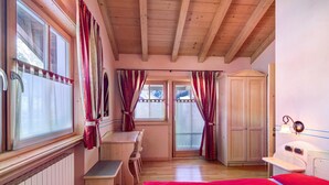 A bedroom with a bed, a desk, a chair, a wardrobe, and a window with curtains. - Chalet Betty Apartment Sgembro with Mountain View (Livigno)