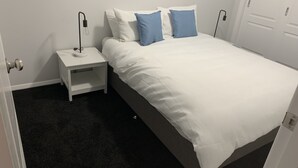 A bedroom with a bed, white nightstands, a lamp, and a door. - YARRAWONGA PARK COTTAGE<br>Cozy 2 bedroom cottage on small acreage  (Mudgee)