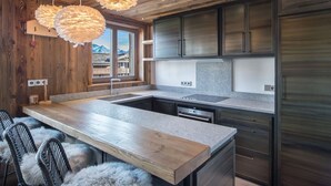 A modern kitchen with a large island, wooden ceiling, and mountain views. - 4-bedroom apartment for 10 in central Courchevel 1850 (Courchevel 1850)