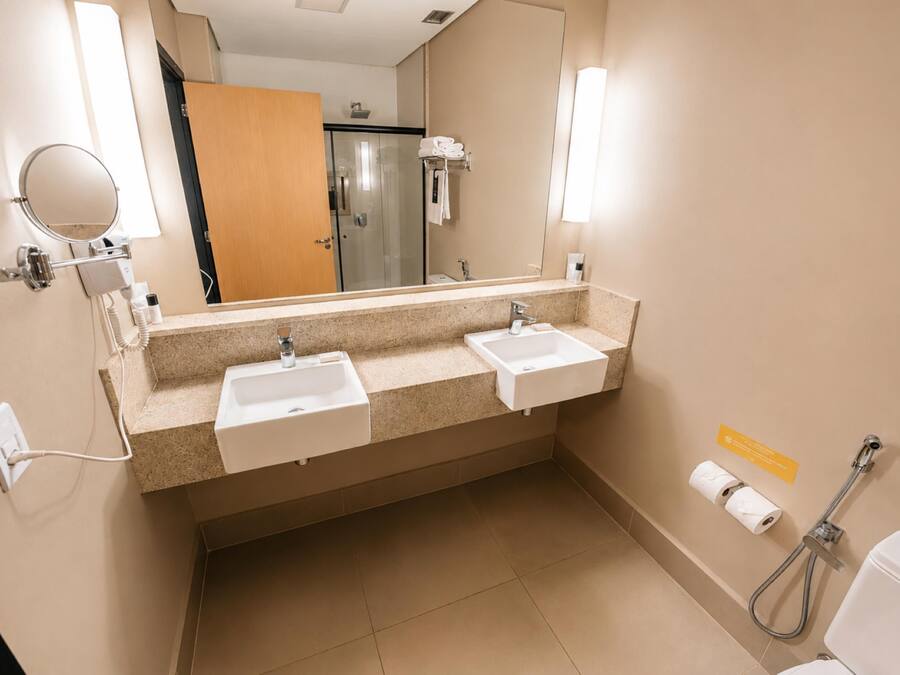 Un baño con dos lavamanos, un espejo, toallero, ducha e inodoro.
