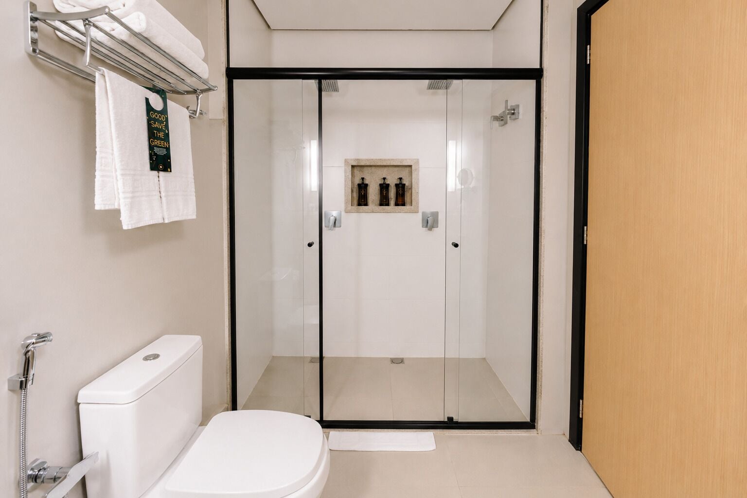 A modern bathroom with a glass-enclosed shower, a toilet, and a towel rack with folded towels.
