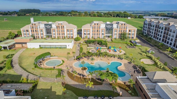 A hotel with a swimming pool, outdoor seating, and a large lawn.