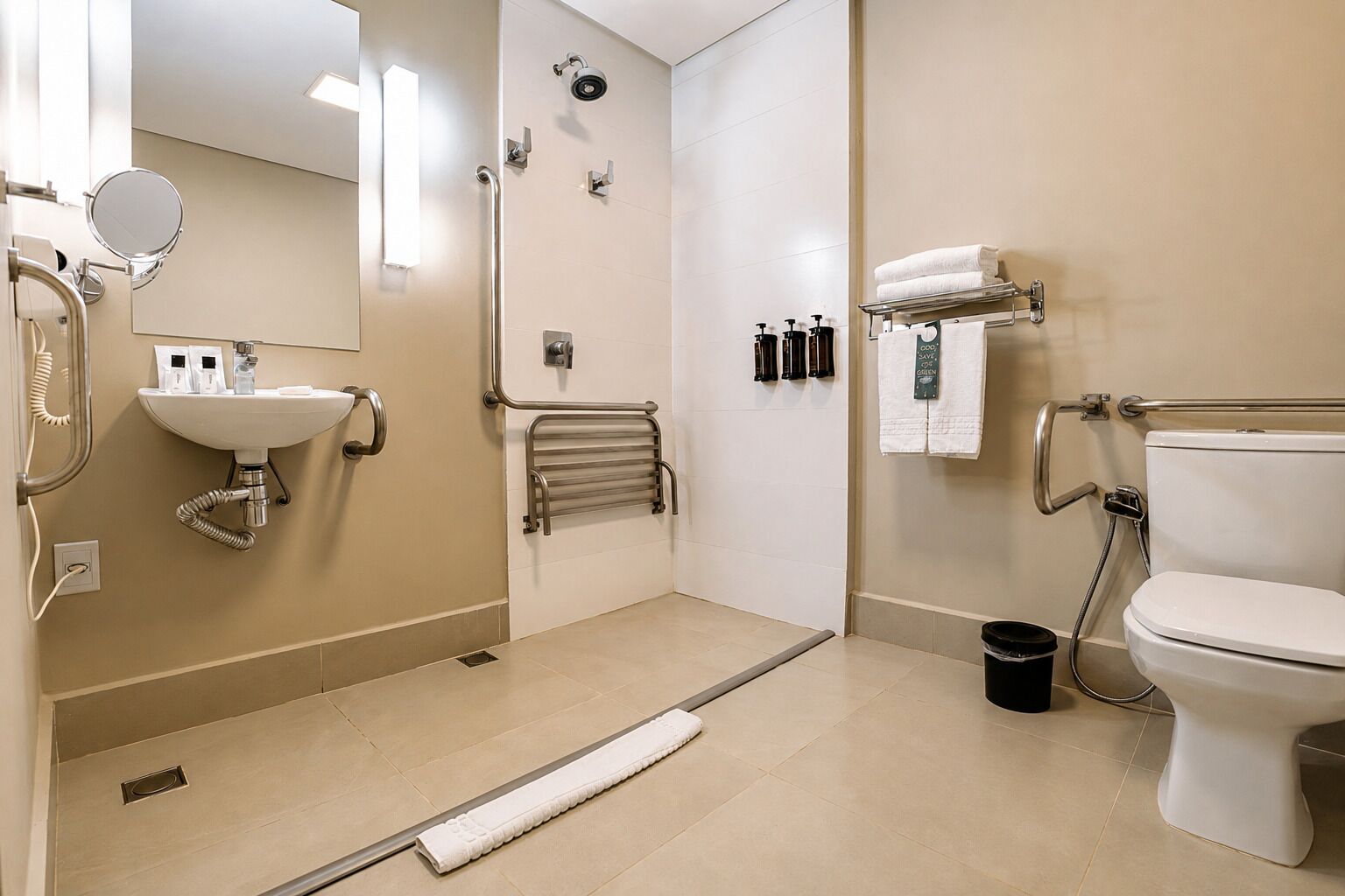 A modern bathroom with a sink, mirror, toilet, shower, and handrails.