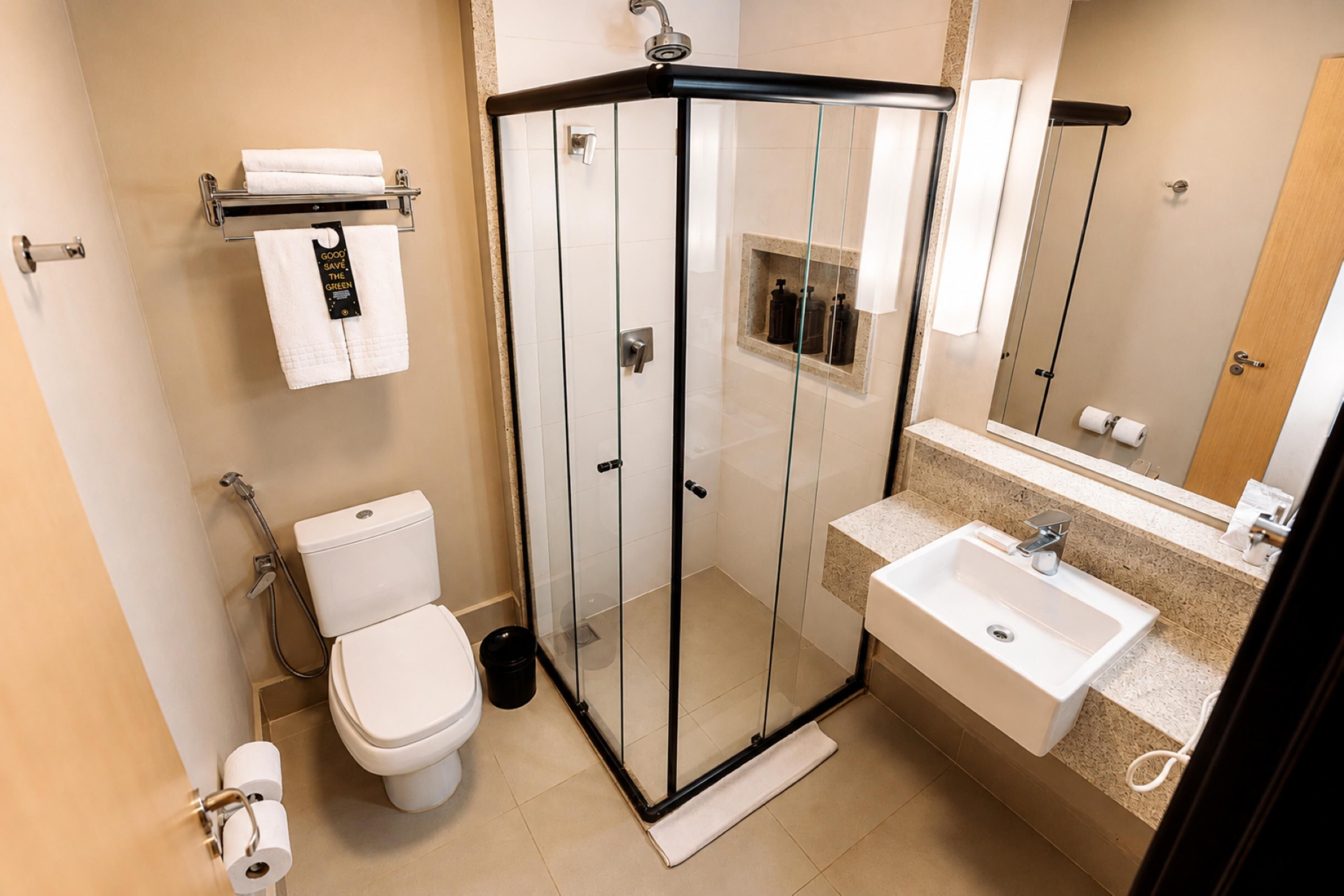 Une salle de bain moderne avec une douche à parois de verre, des toilettes blanches, un lavabo et un miroir.