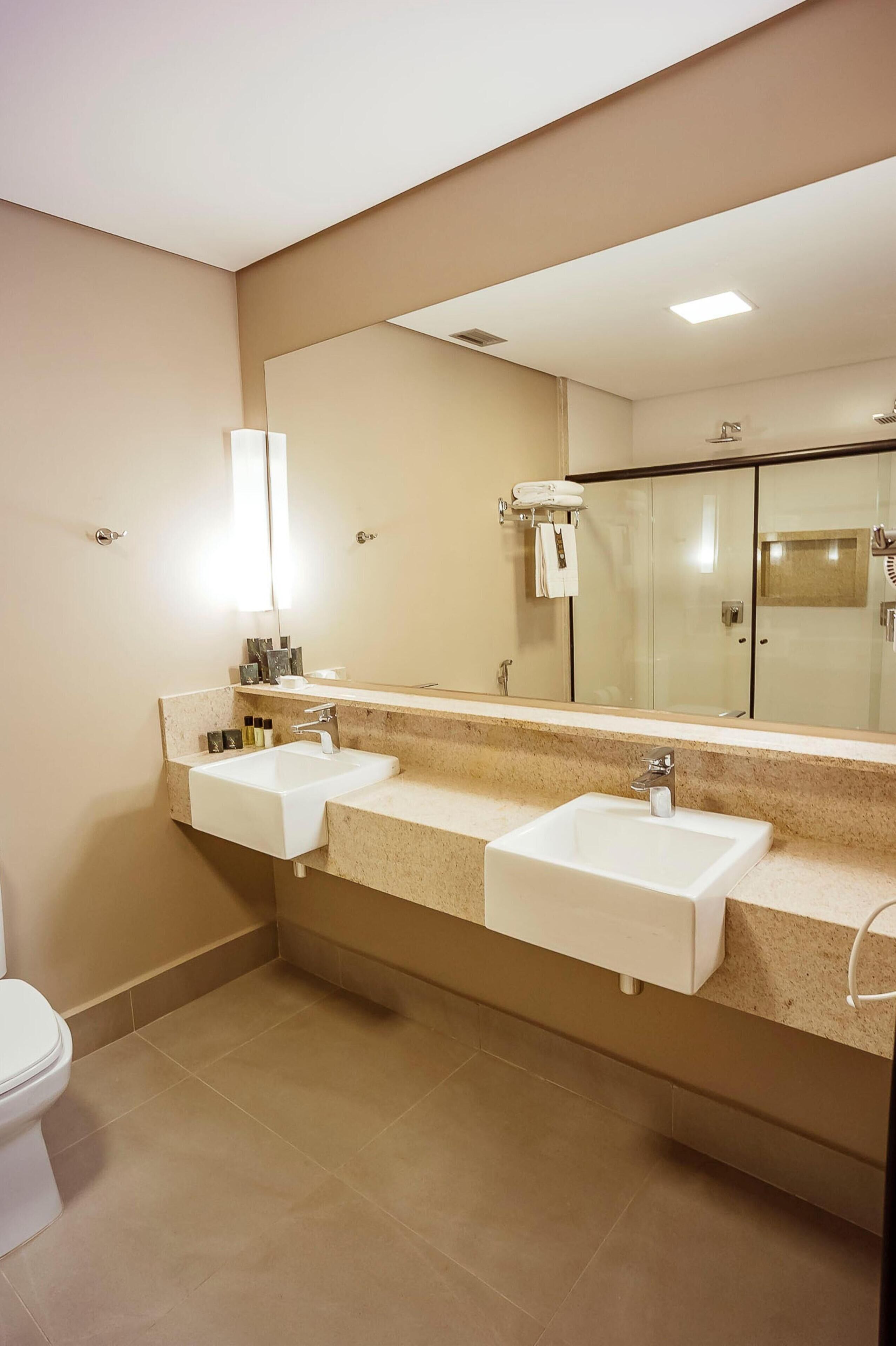 Un baño con dos lavamanos, un espejo grande y una ducha.
